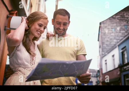 The world is a book with every page worth reading. a happy young couple reading a map while exploring a foreign city together. Stock Photo