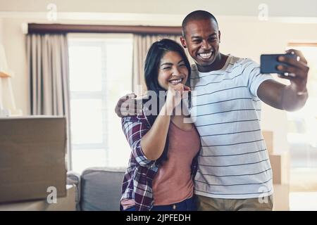 Guess who just got the keys. a young couple taking a selfie in their new home. Stock Photo