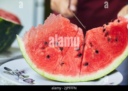 Juicy red watermelon is cut with a knife. The concept of summer and delicious vegetables. Front view. Stock Photo