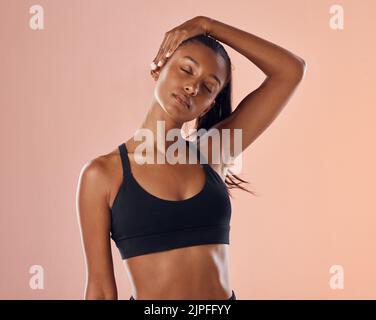 Slim, fit and stretching exercise of a woman feeling confident about her body and health against a pink studio background. Sporty and active woman Stock Photo