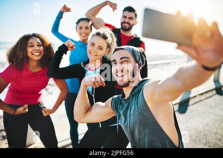 Its a blast to work out with friends. a fitness group taking a selfie while out for a run on the promenade. Stock Photo