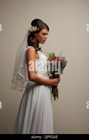 The most gorgeous bride. Studio shot of a young beautiful bride posing against a grey background. Stock Photo
