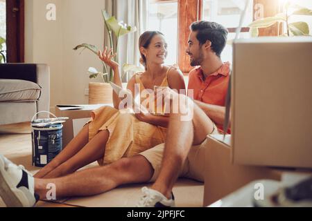 Home owner couple taking a break from painting, moving into new house or remodeling living room interior design. Husband, wife searching home Stock Photo