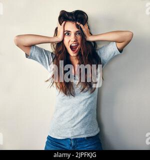 Theres no reason behind my madness. Studio shot of an attractive young woman posing with her hands in her hair. Stock Photo