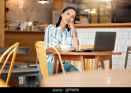 Thinking, wondering and thoughtful female entrepreneur working in a coffee shop planning a mission or vision. Young woman doing remote work in a cafe Stock Photo