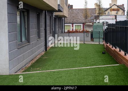 Slough, Berkshire, UK. 17th August, 2022. Fake grass outside a block of apartments in Slough leaves a bland wildlife free environment. Credit: Maureen McLean/Alamy Stock Photo