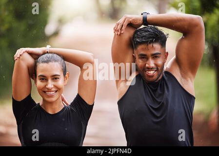 Healthy, fit and motivated couple stretching, warming up or training together in green park with bokeh background. Faces of athletic man and woman Stock Photo
