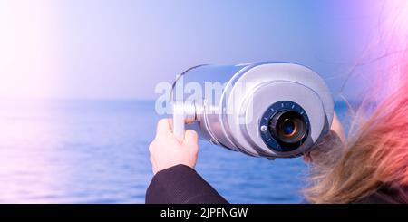 Tourist looking through coin operated binoculars. Binocular telescope on the observation deck for tourism. Sea background. Binoculars watching at horizon at ship deck. Discover new places Travel tourist destination attraction. Copy space for text. Sopot on the pier Stock Photo