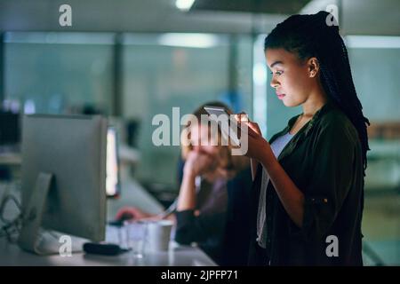 My device has all my employees tasks on it. a young businesswoman using a tablet at the office. Stock Photo