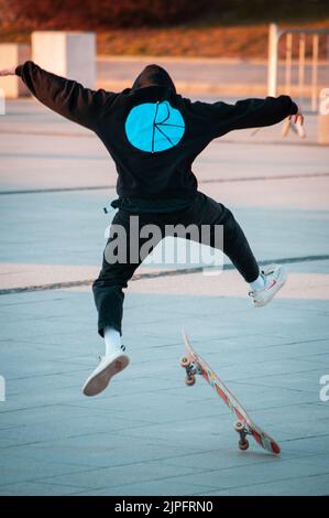 Young man in a hoodie jumping on na skateboard on concrete Stock Photo