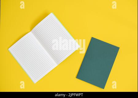 top view of an open notebook, on a  bright yellow background with green notebook on the side Stock Photo