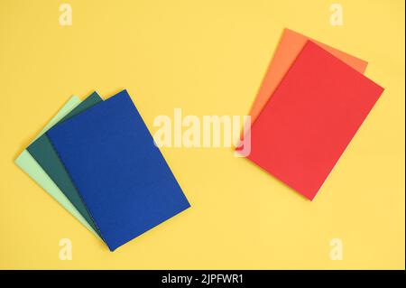 notebooks in different colors on bright yellow background from above Stock Photo
