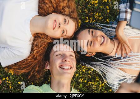 Caucasian vlogger group portrait smiling looking at smartphone camera watching videos on tiktok mobile app. Giving updates about their lifes. Stock Photo