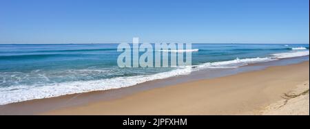 A peaceful scene of surf waves rolling onto a sandy beach along the shore at Kawana on the Sunshine Coast Queensland Australia on a sunny winter day. Stock Photo