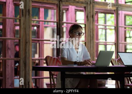 Focused, concentrated female employee working on laptop computer in open-plan office Stock Photo