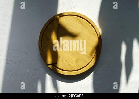 Empty wooden round board on the kitchen table. Wooden pizza plate, a place to copy. View from above. Mockup Stock Photo