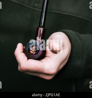 The close-up view of a retro smoking pipe in the left hand Stock Photo