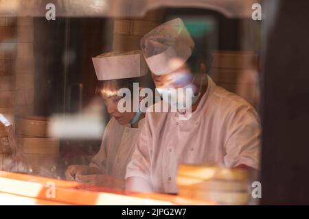 Two chefs working through a window in Chinatown of London Stock Photo