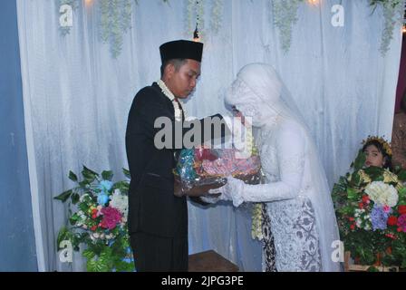 Tegal, INDONESIA - August 17, 2020: The bride receives a gift from the groom while kissing the groom's hand Stock Photo