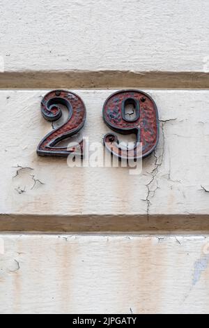 Number twenty nine on white painted plaster wall Stock Photo