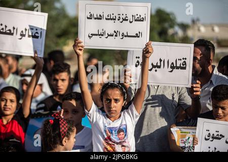 Gaza, Palestine. 17th Aug, 2022. Children hold placards with messages, calling for children's protection at the site where 5 children of the Najm family were killed in the latest Israeli attack on Gaza. Palestinians hold a vigil at the Fallujah cemetery near Jabalia refugee camp in the northern Gaza Strip. The vigil comes in the wake of Israeli officials' recognition of the killing of five children in an Israeli air strike on the Fallujah cemetery, west of Jabalia refugee camp in the northern Gaza Strip. Credit: SOPA Images Limited/Alamy Live News Stock Photo