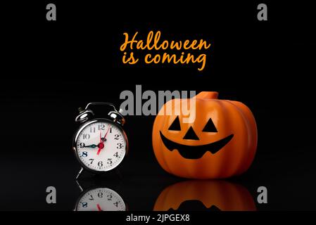 Halloween is coming. Toy pumpkin next to a clock symbolizing the approaching Halloween holiday. Time to dress up as a witch or zombie Stock Photo
