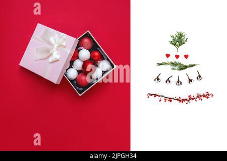 Decorations in pink gift box and creative Christmas tree as symbol of New Year. Top view of round toys on red background. Tree made from twigs of thuja, cotton, red hearts. Copy Space. Soft focus Stock Photo