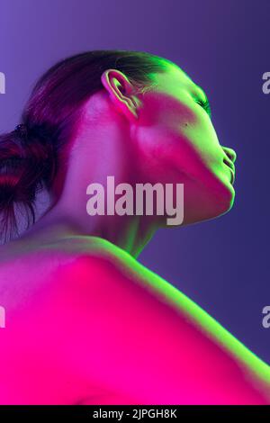 Close up female neck and shoulders in pink neon light over dark background. Natural beauty, fitness, diet, spa, aesthetic cosmetology Stock Photo