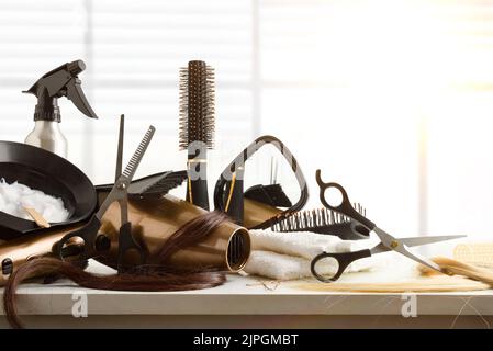 Hairdressing accessories on white workbench in hairdressing salon with window in the background. Front view. Horizontal composition. Stock Photo