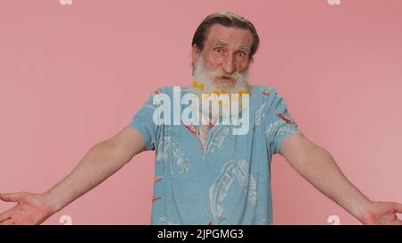 What Why. Sincere irritated mature man raising hands in indignant expression asking reason of failure demonstrating disbelief by troubles. Senior confused grandfather isolated on pink wall background Stock Photo