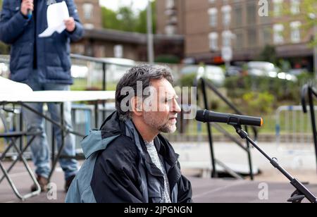 bearded and gray-haired man speaks in front of microphone Stock Photo