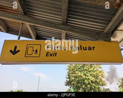 An exit sign from a train station with a yellow background in Indonesia Stock Photo