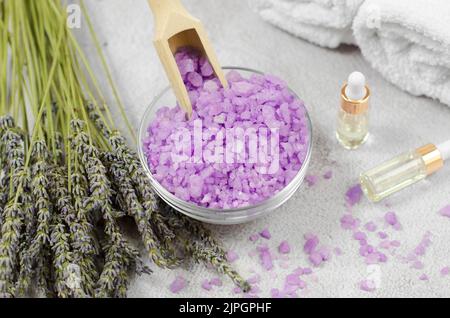 Light purple sea salt and lavender bouquet against the background of essential oils and bath accessories. Spa composition Stock Photo