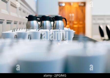 A Conference Room Table with Empty Tea Mugs and Coffee Thermoses Stock Photo