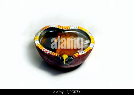 A Close up image of a lit clay diya or lamp on floor on Diwali - an Indian hindu festival of lights isolated on black background. Stock Photo