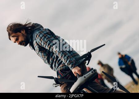 Man pilot holding quadcopter drone in hands at outside field Stock Photo