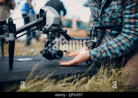 Man pilot checking quadcopter drone camera before aerial flight and filming Stock Photo