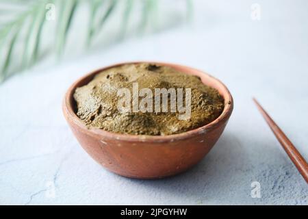 The wooden bowl with rehydrated henna on table Stock Photo