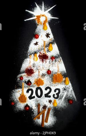 Multiple spices and powdered sugar in the form of a christmas tree and 2023 number isolated on black background Stock Photo