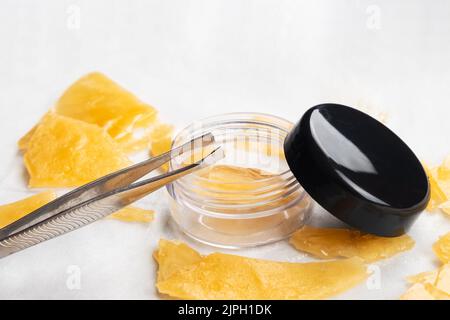 golden pieces of cannabis extract distillate and tweezers, high thc. Stock Photo