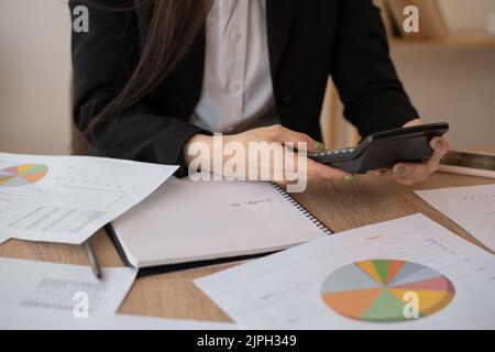 Close up of a female hand calculating financial expenses with calculator on the office desk. hispanic self employed woman checking bills and budget Stock Photo
