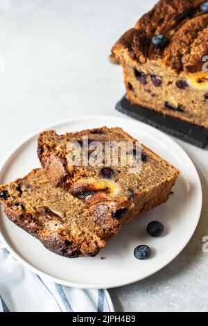 Slices of banana bread with blueberries served on a plate on a gray background. Stock Photo