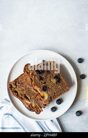 Slices of banana bread with blueberries served on a plate on a gray background. Top view. Stock Photo