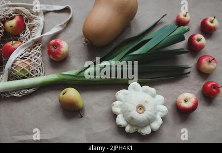 autumn harvest with sqush, pumpkin, red apples in a mesh shopping eco bag. zero waste, no plastic concept Stock Photo