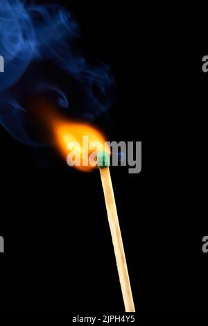 The moment of ignition of sulphur of a match with blue smoke on a dark background Stock Photo