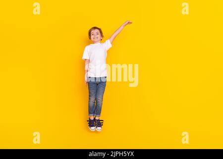 Full length body size view of handsome cheerful funny pre-teen boy jumping measuring copy space isolated over vivid yellow color background Stock Photo