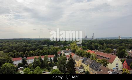 A drone shot of colorful roofs, and trees with a chemical plant on the horizon, Marl, Germany Stock Photo