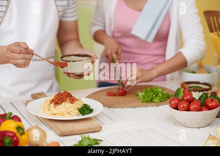 Man adding bolognese sauce on plate with pasta Stock Photo