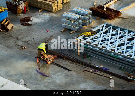 A construction worker uses an angle grinder to cut metal in construction area Stock Photo