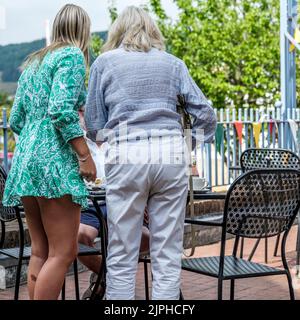 Dorking, Surrey Hills, London UK, August 18 2022, Mother And Daughter Standing with Back To The Camera On An Outside Cafe Terrace Stock Photo